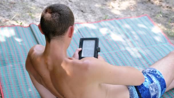 Masculino Lendo Book Cobertor Colorido Enquanto Relaxa Praia Vista Traseira — Vídeo de Stock