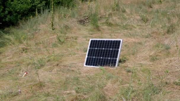 在大自然的草地上安装了一个小型便携式光电太阳能电池板 在夕阳西下 黑色面板在阳光下消耗太阳能 在室外使用生态能源 — 图库视频影像