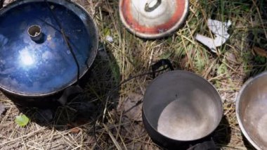 Kamp için Bulaşık, Ot, Bowl ve dışarıda yemek pişirmek için Kızartma Tavası. Kirli, yıkanmamış tencereler ve bulaşıklar güneşte çimlerde yatıyor. Mutfak gereçleri. Seyahat, seyahat, ormanda tatil kavramı