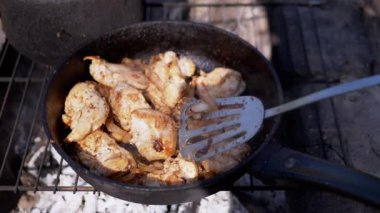 Doğa 'da Kızartma Tavasında Etli Izgara Pişiriyorum. Eti bir spatulayla karıştırır. Dışarıda yanan bir ateşin üstünde yemek, odun, duman. Konsept kamp, turizm, gezi. Barbekü ızgarası.