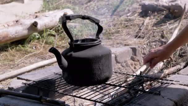 Erkek Izgaranın Üzerinde Kaynayan Bir Çaydanlıkla Ateşte Kurumuş Dallar Bırakıyor — Stok video