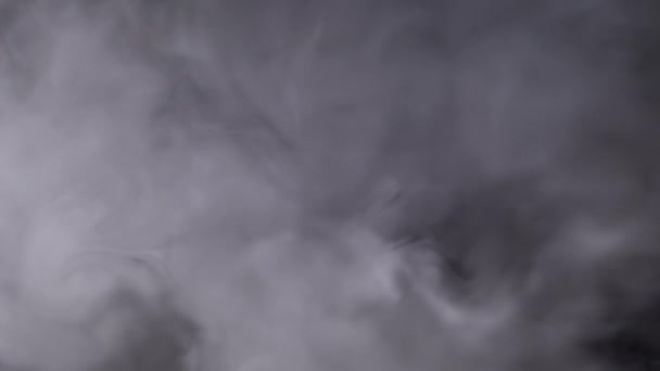 スモークや蒸気の厚い氷の雲のプランは ブリュリーモーションでスペースを満たします ヴァイプからの煙の雲の柔らかい灰色のカールの渦 タバコは黒い背景に溶けます テクスチャー フルフレーム — ストック動画
