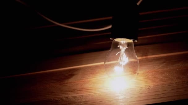 Hand Legt Eine Glühbirne Auf Einen Holztisch Einem Dunklen Rauchigen — Stockvideo
