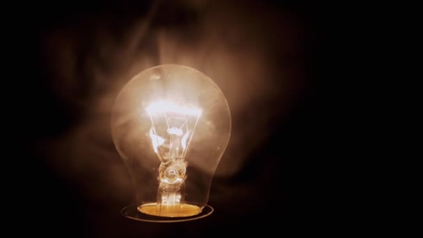 Одна Светящаяся Лампочка Накаливания Густом Дыму Черном Фоне Закрывай Дасти — стоковое видео