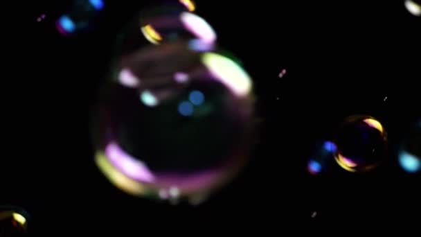 彩色的肥皂泡在空旷的空间中 在孤立的黑色背景下飞舞 五彩缤纷的灯光许多彩虹透明气泡随机旋转 模糊的动议 有选择的重点 — 图库视频影像