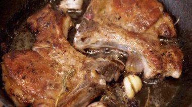 Yaklaş, Kızartma Tavası yağında kemikli Sulu Domuz Bifteği. Kahverengi kıtır etli biftek, biberiye, sarımsak, karabiber, baharat. Doku. Ağır çekim. Lezzetli yemek..