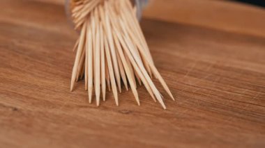 Dağıtılmış kürdan, tahta bir arka planda döner. Kapatın. Plastik bardakta bambu ahşap kürdan seti. Yemekten sonra evde ağız bakımı. Diş temizliği. Bulanık hareket. Dişçi konsepti. Döngü.