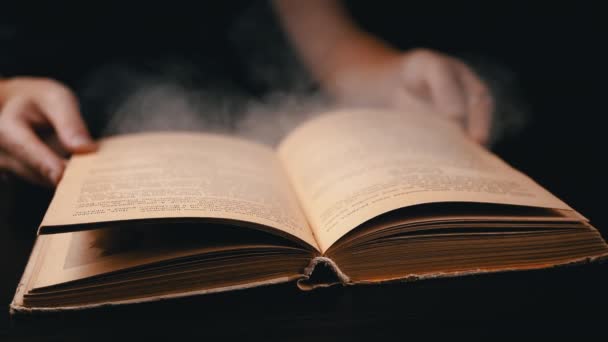近づいて 少女は暗くてスモーキーな部屋の古い本のページを飛び越える 煙の雲について 屋内で喫煙する 夜に面白い本を読んでいる 神秘的な雰囲気 ブラックバック スローモーション — ストック動画