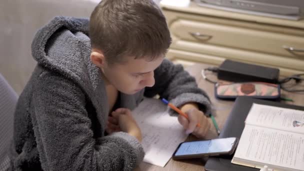 Poważny Nastolatek Szacie Siedzący Przy Biurku Odrabiający Lekcje Pomocą Smartfona — Wideo stockowe