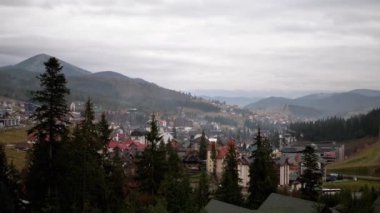 Sonbaharda Bukovel 'de tatil. Karpatlar 'ın panoramik manzarası, köy, modern otellerin çatıları, binalar. Altyapı tesisleri, kafeler, restoranlar. Tepeler, sis. Bulutlu. Kayak kaldırma.
