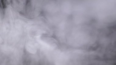 Kalın Buzlu Duman Bulutları veya Buhar Boşluğu Bulanık Hareketlerle Doldur. Yumuşak beyaz duman kıvrımları, sigara siyah arka planda erir. Doku. Tam çerçeve.