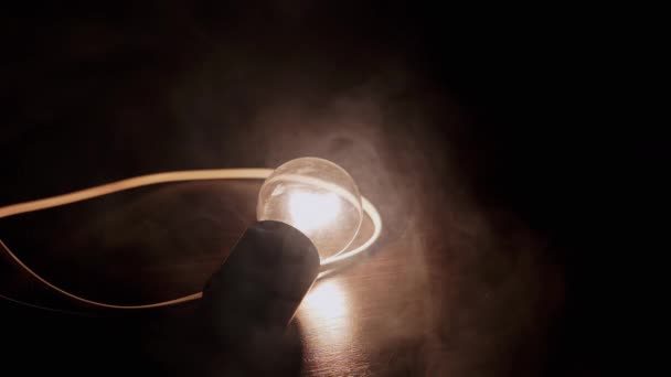 Jedna Zářící Žárovka Drátem Leží Dřevěném Stole Kouři Textura Pozadí — Stock video