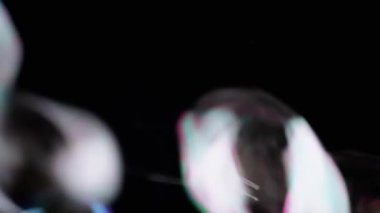 Bir sürü renkli sabun köpüğü Kara Arkaplanda uçuşuyor ve patlıyor. Üfleme. Sıçra, köpük. Hızlı bulanık hareket. Soyut, dokulu. Seçici odaklanma. Boşluk. Siyahta izole edilmiş. Işıklandırma.