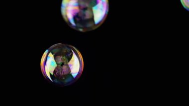 Bir sürü renkli sabun köpüğü Kara Arkaplanda uçuşuyor ve patlıyor. Üfleme. Sıçra, köpük. Bulanık hareket. Büyük, küçük sıvı şekiller. Soyut, renkler. Odaklan. Boşluk. Siyah üzerine izole edilmiş..