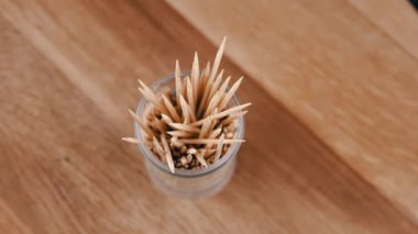 Kürdanları plastik kupada tahta zeminde döndür. Kapatın. Üst Manzara. Bir sürü keskin bambu ahşap kürdan. Yemekten sonra evde ağız bakımı. Diş temizliği. Bulanık hareket. Diş hekimi kavramı.