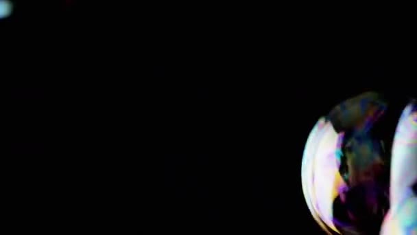 在空旷的空间里 有许多色彩斑斓的肥皂泡在黑色背景下飞舞 靠近点震动透明的发光球体 模糊的运动 选择性的聚焦 被隔离在黑暗中 — 图库视频影像