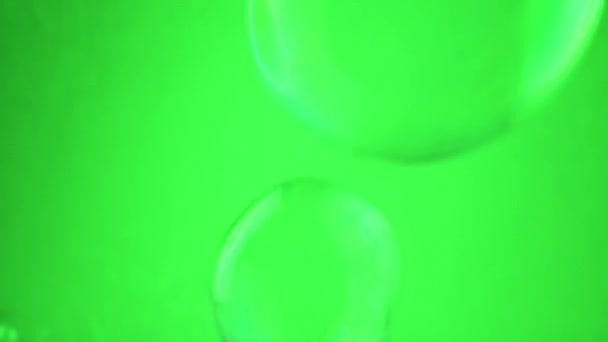 閉じる 多くの大きな石鹸の泡は 空のスペースの緑の背景に飛んでいます 透明な虹彩の球を吹き飛ばしています 抽象的 テクスチャー ブレイクされた動き 選択的な焦点 孤立した クロマキー — ストック動画