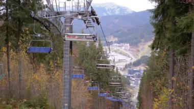 BUKOVEL, UKRAINE, 2023: Boş Kayak Asansörleri Karpat Dağları 'nın Arkaplanına Karşı İlerliyor. Panoramik manzara. Vadi, köy kasabası. Bir dağın tepesinde, orman. Bulutlu. Bukovel 'de kayak merkezi.