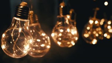 Smoke on a Black Background 'da Parlayan Vintage Edison ampullerini asmak. Ilık ışık. Doku, yapı. Noel süslemeleri, klasik elektrik ampulleri, retro tarzı çelenkler mekanı aydınlatıyor.