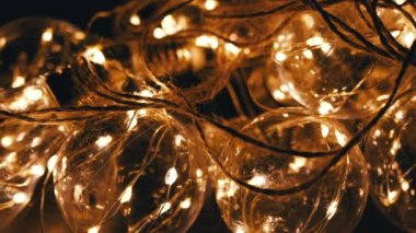 Karanlık Oda 'da Sim Yellow Light ile Parlayan Cam Ampul Çelengi. Kapatın. Doku. Bir sürü. Alanı aydınlatan elektrik lambaları asılan retro tarzı Noel süslemeleri. Tasarım.