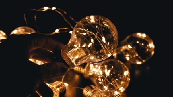 手は輝く電球の背景にフリッカーリングライトバルブを保持します 暖かいライト テクスチャー クリスマスの装飾 レトロなスタイルのヴィンテージ電球は 暗いスペースを照らします ダーク ダーク — ストック動画