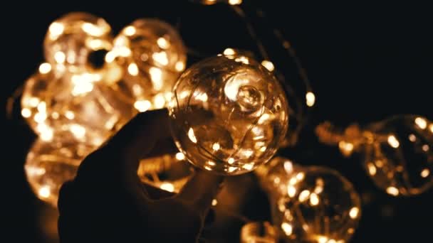 Ręka Trzyma Żarówkę Tle Girlandy Świecących Żarówek Ciepłe Światło Teksturę — Wideo stockowe