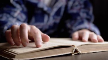 Kadın parmağını bir kitap sayfasında gezdiriyor, Karanlık Oda 'da metni hızlıca okuyor. Kapatın. Seçici odaklanma. Geceleri lambanın altında edebiyat okumak. Evde eğitim al. Gölge. Yatak odası. İyi akşamlar..