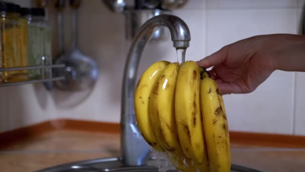 在厨房里 手洗香蕉在流水下 背景模糊不清 靠近点在进食前清除病毒 细菌和泥土中的水果 掉下来的水滴 安全和准备 — 图库视频影像