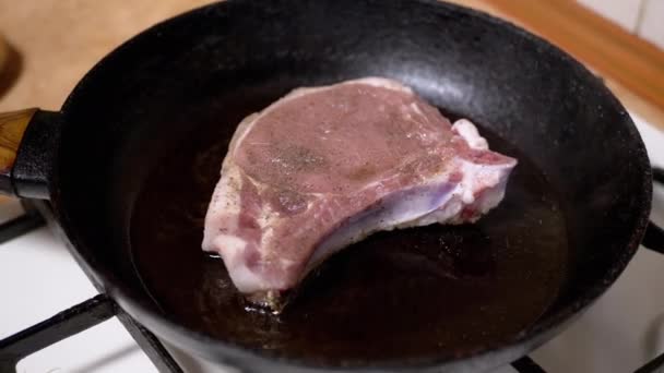 生肉片在热腾腾的热腾腾的锅里与沸腾的油一起煎 靠近点纹理 用褐色脆皮和家庭厨房里的调味品在骨头上烹调猪肉牛排 美味的晚餐 — 图库视频影像