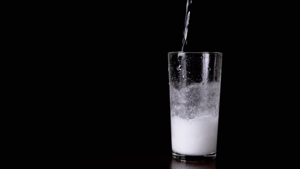 在黑色背景上玻璃波束中苏打和醋的化学反应 液体与混合物一起倒入玻璃杯中 二氧化碳 气泡的形成 化学实验 — 图库视频影像