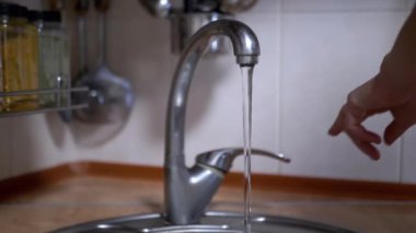 Mutfakta Çeşme Suyu ile Bulanık Arkaplanda Musluğu Kapat. Kapatın. Temiz, şeffaf su lavaboya akar. Ağır çekim. Tüketim, evde doğal su kaynaklarının korunması.