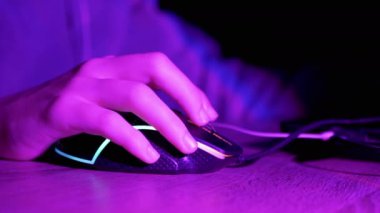 Oyuncu, geceleyin Sanal Oda 'da Bilgisayar oyunu oynuyor. Kapatın. Elli oyuncu bir bilgisayar faresinin düğmesine basar. İnternetteki eSports yarışması. Neon arka ışık, klavye. Hacker ya da serbest çalışan.