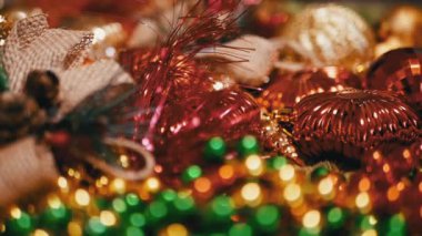 Yakın plan, Noel arkaplanındaki Altın ve Kızıl Noel Baloları. Bir sürü pırıl pırıl parlak yeni yıl mücevheri. Slayt atışı. Bulanık hareket. Döngü. Noel süsleri. Seçici odak.