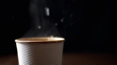 Siyah bir arka planda kağıt bardakta sıcak çay demlemek. Sıcak kaynar su damlaları çay fincanına dökülüyor. Buhar. Yavaş çekim, aydınlatma. Uzayı kopyala Paket içki. Yan görüş, izole edilmiş. Kahve..