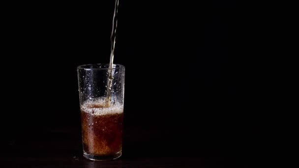 ブラックバックグラウンドのウェットグラスにホットティー ドリンク またはウイスキーを注ぐ クローズアップ 熱い沸騰した水の流れ テクスチャー 孤立した 透明なカップから泡が流出する泡 — ストック動画