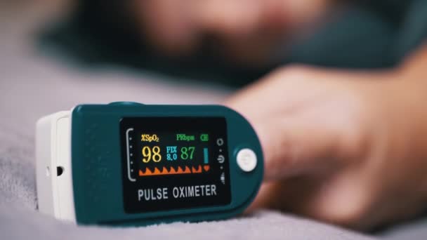 用脉冲血氧计测量儿童手指血液中的氧含量 靠近点拨号与传感器 指示器上的数字装置在模糊的背景 晚安该睡觉了熟睡的孩子 — 图库视频影像