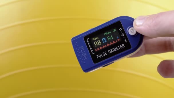 在运动过程中 用手用脉动血氧计测量脉搏和氧饱和度 靠近点拨通装置上的传感器和指示器 心率的测量 黄色背景 健康球 — 图库视频影像