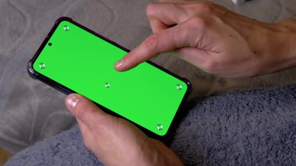 ベッドタイムの部屋の緑色のスクリーンとスマートフォンを握る女性の手 指はタッチ画面に触れ パスワード コードをダイヤルします コピースペースのためのクロマキーレイアウト 携帯電話のロックを解除する — ストック動画