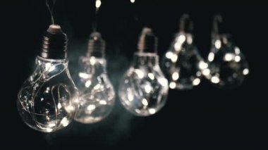 Smoke on a Black Background 'da Parlayan Vintage Edison ampullerini asmak. Ilık ışık. Doku, yapı. Noel süslemeleri, klasik elektrik ampulleri, retro tarzı çelenkler mekanı aydınlatıyor.