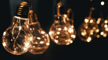 Smoke on a Black Background 'da Parlayan Vintage Edison ampullerini asmak. Ilık ışık. Doku, yapı. Noel süslemeleri, klasik elektrik ampulleri, retro tarzı çelenkler mekanı aydınlatıyor.