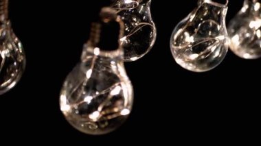 Parlak Vintage Edison Ampulleri Siyah Arkaplanda Tavanda Asılı. Arka arkaya. Ilık ışık. Kablo. Noel süslemeleri, klasik elektrik ampulleri, retro tarzı çelenkler mekanı aydınlatıyor.