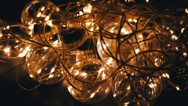 暗い部屋のディムイエローライト付きのガラス灯台の輝くガーランド クローズアップ テクスチャー バンチ スペースを照らす電気ライトを掛けるレトロなスタイルのクリスマスの装飾 デザイン — ストック動画