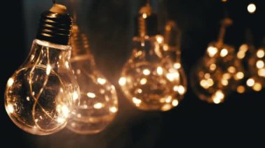 Smoke on a Black Background 'da Parlayan Vintage Edison ampullerini asmak. Ilık ışık. Doku, yapı. Noel süslemeleri, klasik elektrik ampulleri, retro tarzı çelenkler mekanı aydınlatıyor.