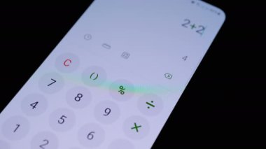 Eller, Kara Arkaplanda Hesap Makinesi Uygulaması olan Akıllı Telefonu Tutar. Kapatın. Mobil bir uygulamaya numaralar ve toplamlar ekleniyor. Kablosuz teknoloji. Finansal muhasebe girişi.