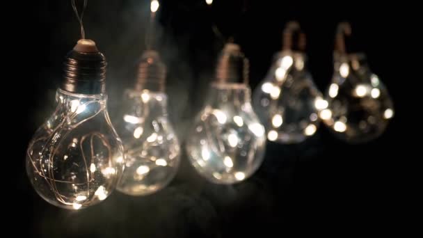 Glühende Edison Glühbirnen Hängen Rauch Auf Schwarzem Hintergrund Warmes Licht — Stockvideo