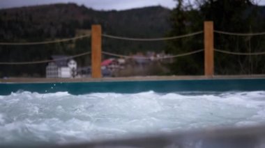 Dışarıdaki termal kaplıcalardan gelen sıcak suyla kaynayan jakuziyi boşalt. Bir damla su, köpüklü çeşme. Jakuzi, Carpathian dağları manzaralı yüzme havuzu. Spa tedavisi. Sağlık Oteli.