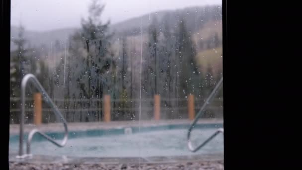 ラグジュアリーホテルの窓から雨天の空のプールまで ブロール ゆったりとしたパノラマウィンドウから沸騰したホットタブへ 森の景色 雨の蒸発 — ストック動画