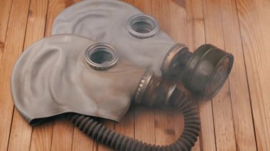 İki Eski Kauçuk Gaz Maskesi Kalın Duman Bulutu 'nda Ahşap Bir Arkaplanda Yatar. Kapatın. İzole edilmiş. Solunum cihazının parçaları. Radyoaktif maddelere karşı koruma, toz, duman ve sis.