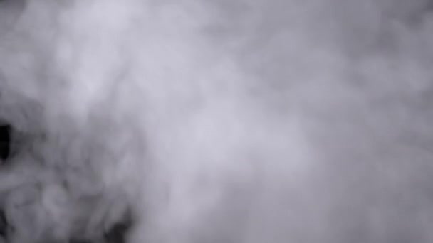 スモークや蒸気の厚い氷の雲のプランは ブリュリーモーションでスペースを満たします 蒸気からの煙の雲の柔らかい白いカールの渦 タバコは黒い背景に溶けます テクスチャー フルフレーム — ストック動画
