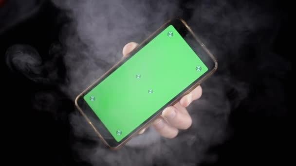 Hand Hålla Mobiltelefon Med Grön Skärm Svart Bakgrund Rök Hand — Stockvideo
